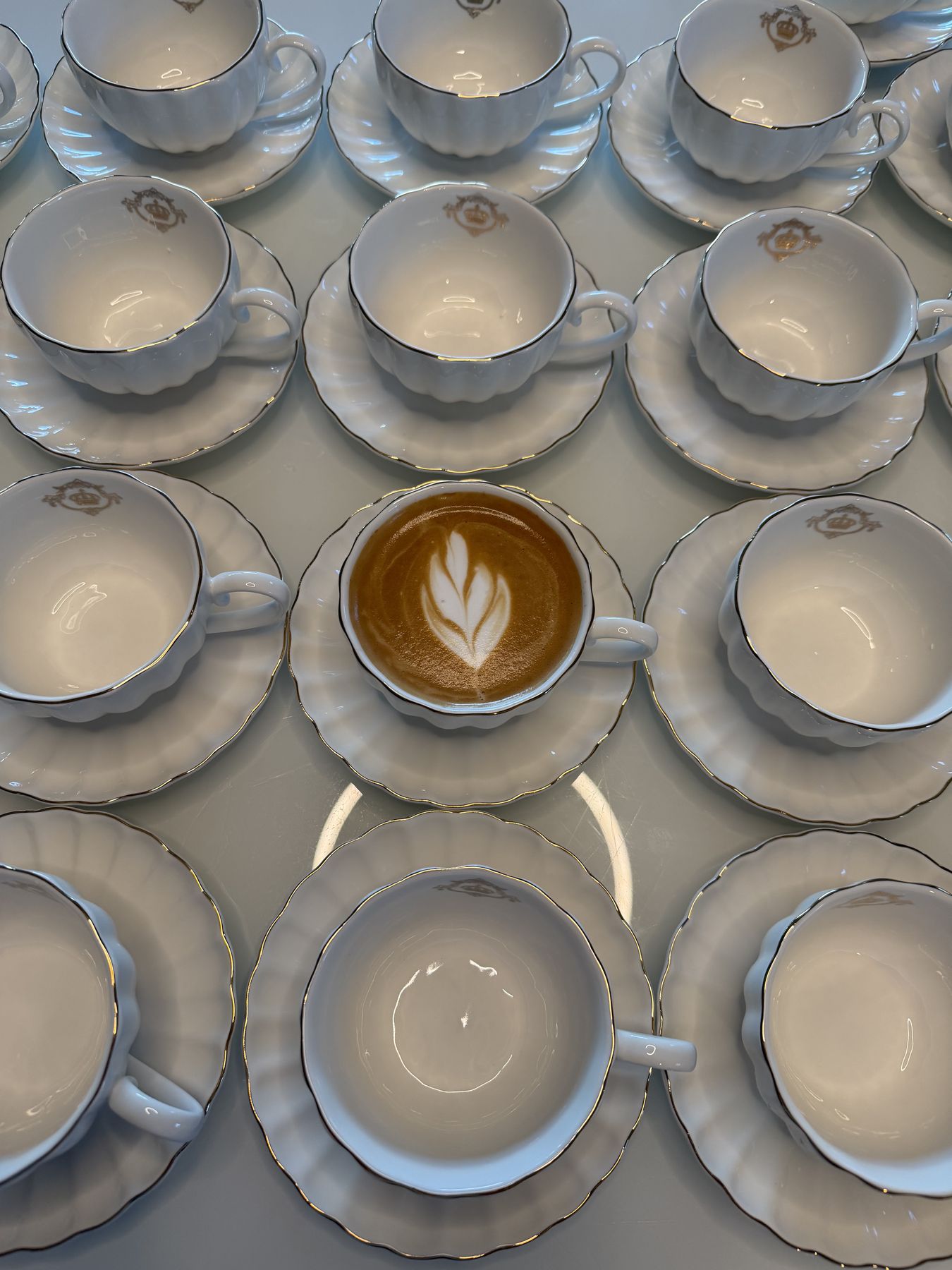 Rows of porcelain cups with a latte at the center