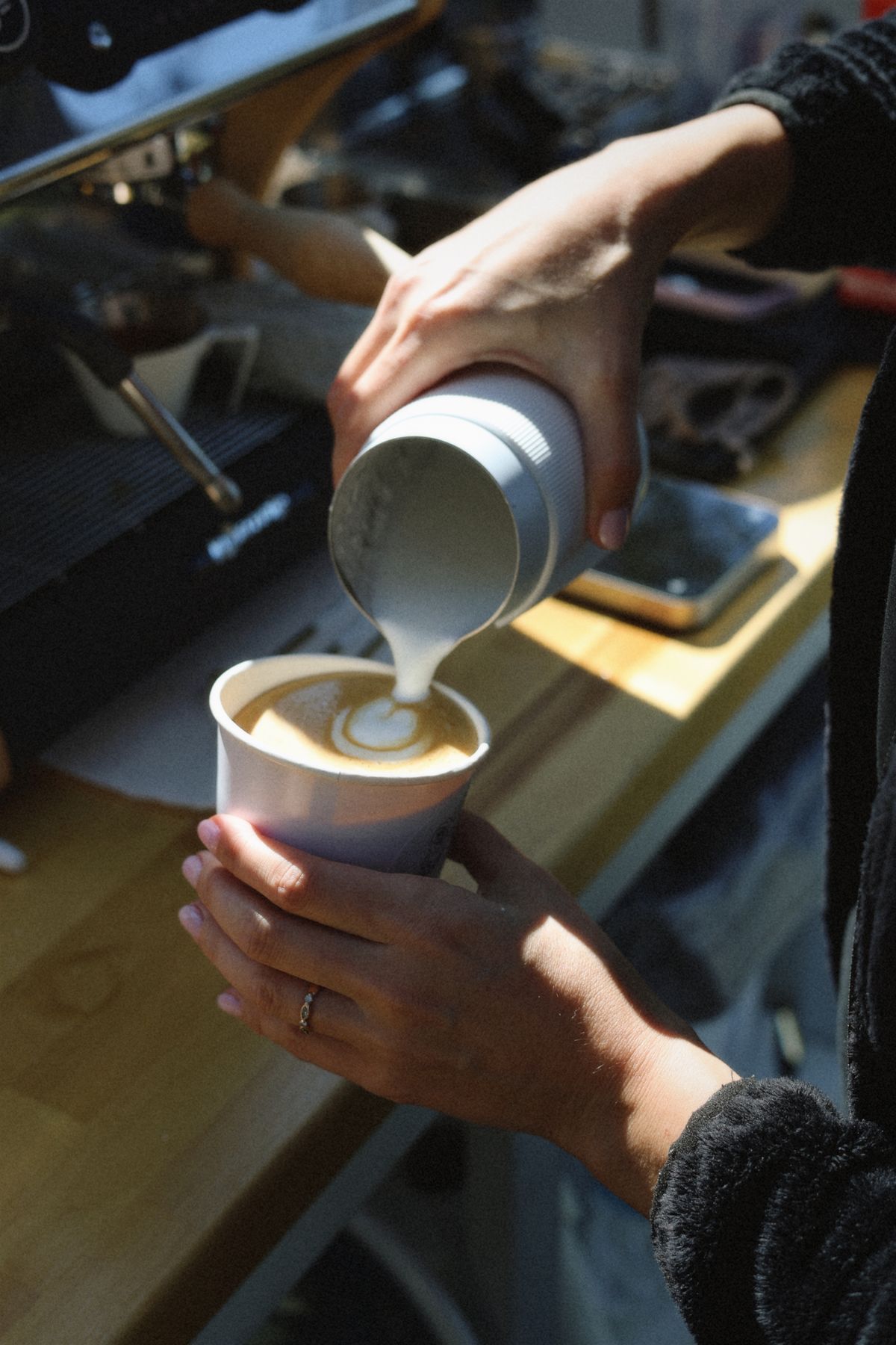 Barista pouring steamed milk into a latte